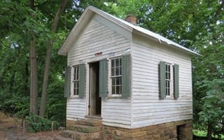 A small square building painted white with green shutters. This was John C. Carter's office and dates to the 1880s.