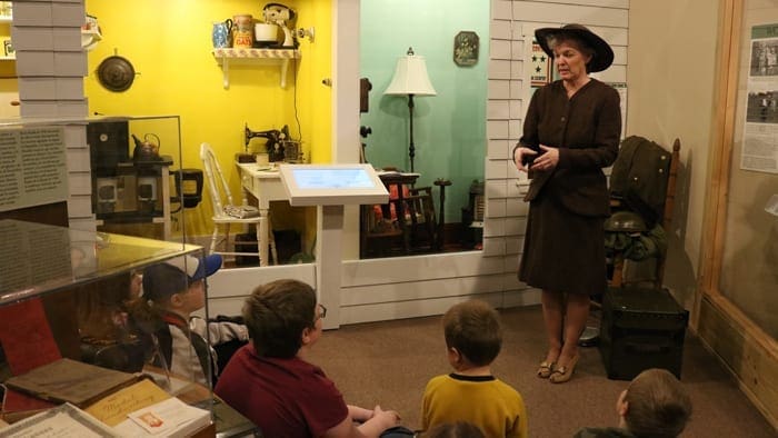 A museum employee speaks to students in front of a display at the Shiloh Museum of Ozark History.