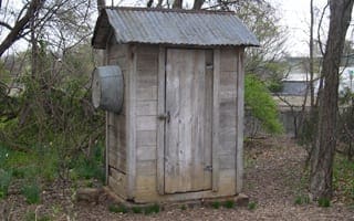 A wooden outhouse with a tin roof. 