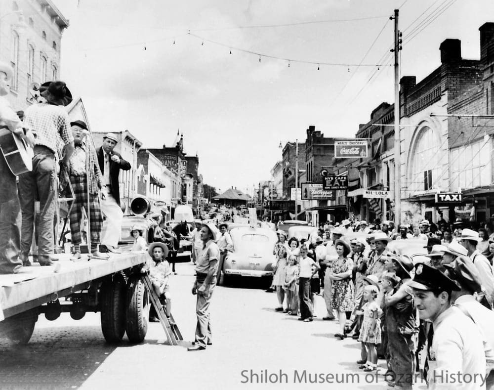 Springdale's Skunk Holler Hillbilly Band promoting the Rodeo of the Ozarks, Van Buren, Arkansas, June 1946. P. W. “Doc” Boone at the microphone, with Shelby Ford (in white hat).