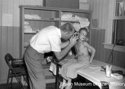 Dr. Joe Parker examining a young girl, Springdale, August 1961.