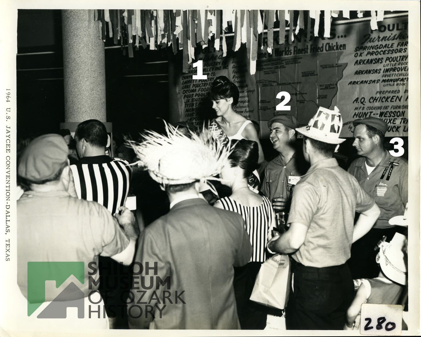 🔍 Calling all History Detectives for #PhotoIDFriday! 📸✨

We need your help identifying the people in this 1964 photo taken at a Jaycees convention in Dallas! Featured here are members of the Arkansas Jaycees posing with "Miss Arkansas Chic."

They could be from Springdale, but we aren't certain. Recognize anyone in this snapshot from the past?

Drop your clues, names, or guesses in the comments below!

(Note: If you share this to your Facebook feed or story, please set the post to public so we can see all the helpful comments!)

Photo is from the Shiloh Museum’s Janice Zulpo Collection (S-2026-20-20).

#PhotoIDFriday #ShilohMuseum #SpringdaleAR #ArkansasJaycees